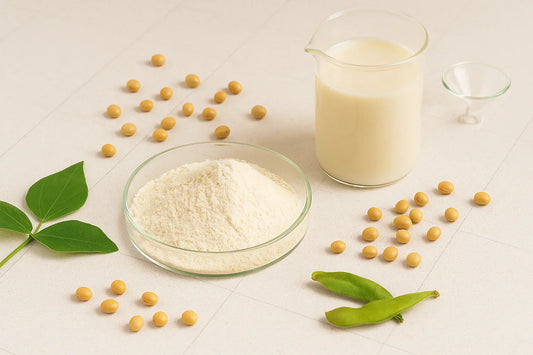 Soy protein isolate powder in a glass petri dish with soybeans, green leaf, pods and a beaker of soy milk on a neutral lab backdrop – Ingredients & Science | Maxine’s Burn Malaysia